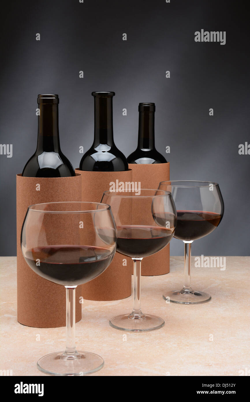 Tre diverse bottiglie di vino e bicchieri da vino sono impostati per un cieco di degustazione di vino. Le bottiglie sono coperti da bombole vuote. Foto Stock