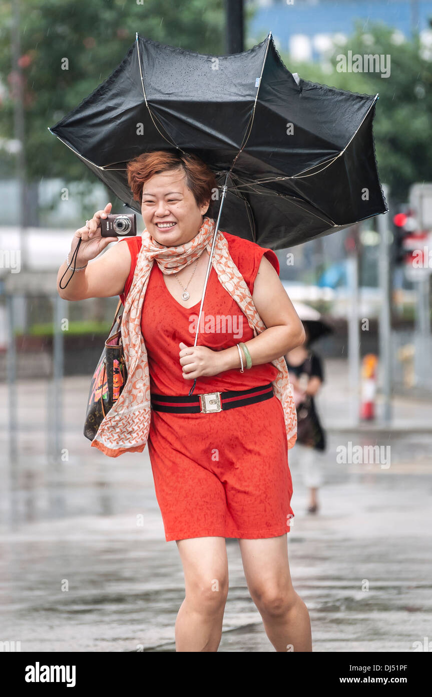 Turisti cinesi con un ombrello rotto scatta foto durante una tempesta tropicale in Hong Kong Foto Stock