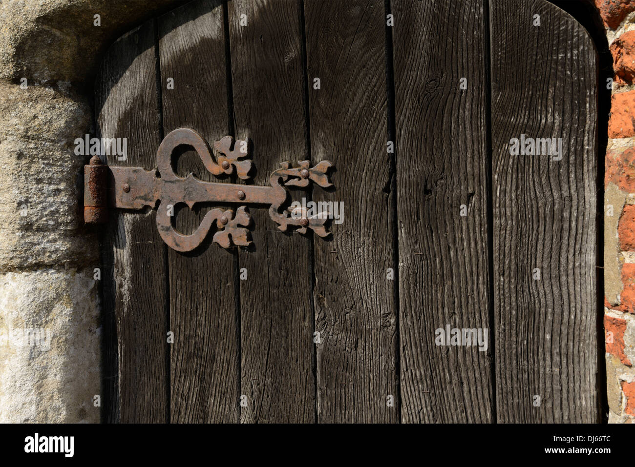 Rusty cerniera su una vecchia porta di legno, la pompa del villaggio, luogo comune, Little Walsingham, Norfolk, Inghilterra, Regno Unito, Europa Foto Stock