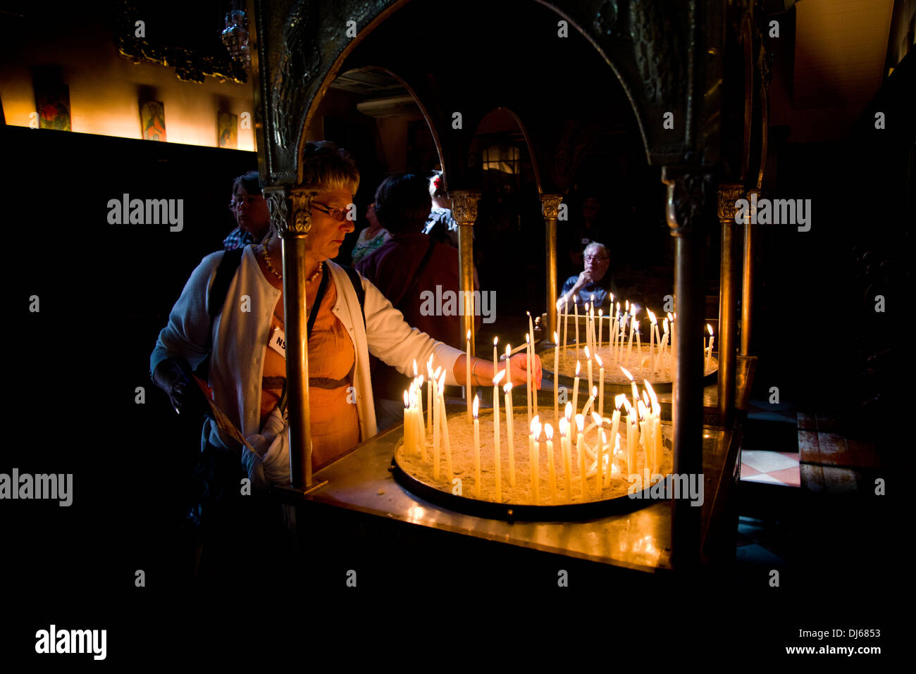 Una donna di accendere una candela in un monastero greco Foto Stock