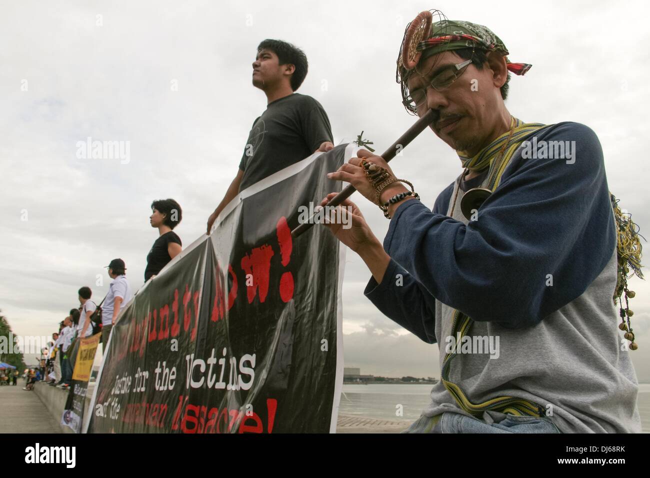 Manila, Filippine. 22 Novembre, 2013. Un manifestante svolge un naso flauto durante la catena umana evento nella baia di Manila nel ricordo dei professionisti dei media che sono stati uccisi 4 anni fa a Maguindanao. -- I membri di diverse organizzazioni multimediali tenuto una catena umana e illuminazione delle candele cerimonia di 34 giornalisti uccisi quattro anni fa. 58 individui sono stati uccisi e sepolti a Maguindanao in uno dei peggiori elezione relativi alla violenza nel paese.Foto: J Gerard Seguia/NurPhoto Credito: J Gerard Seguia/NurPhoto/ZUMAPRESS.com/Alamy Live News Foto Stock