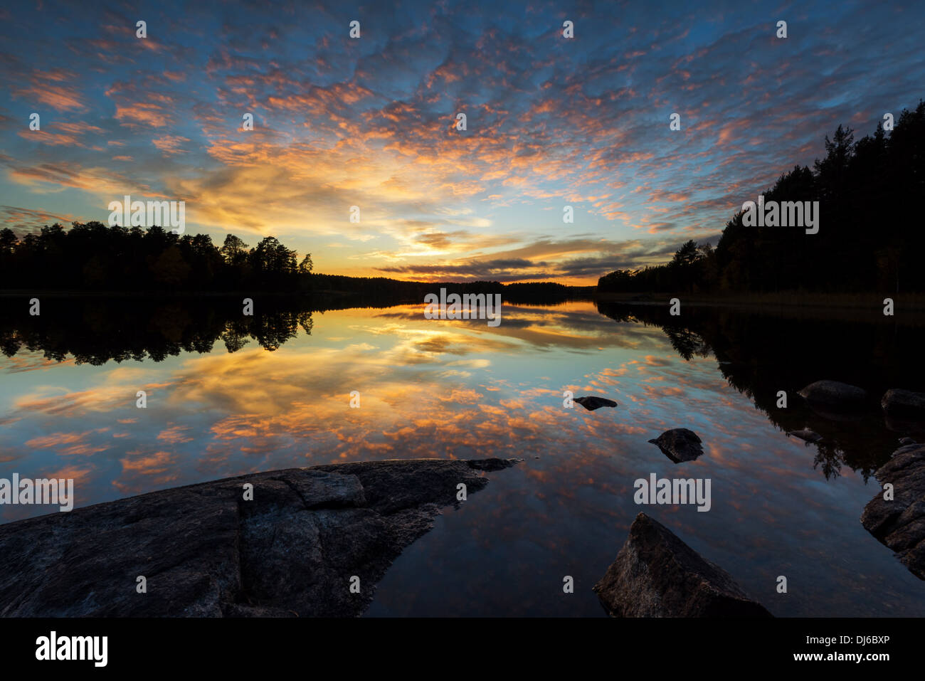 La riflessione del tramonto colorato su di un lago calmo. Foto Stock