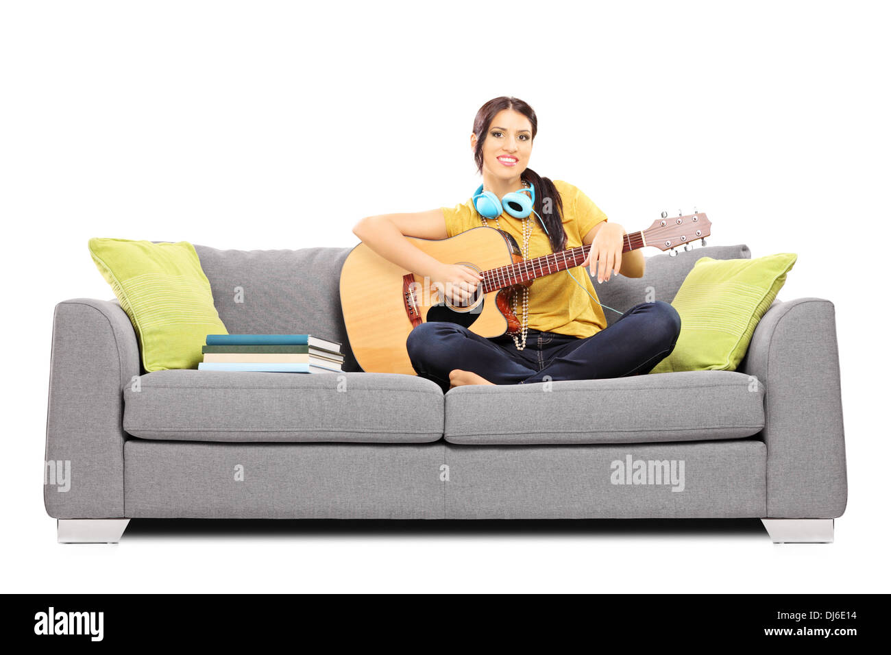 Bellissima femmina musicista seduto su un divano suonando una chitarra acustica Foto Stock