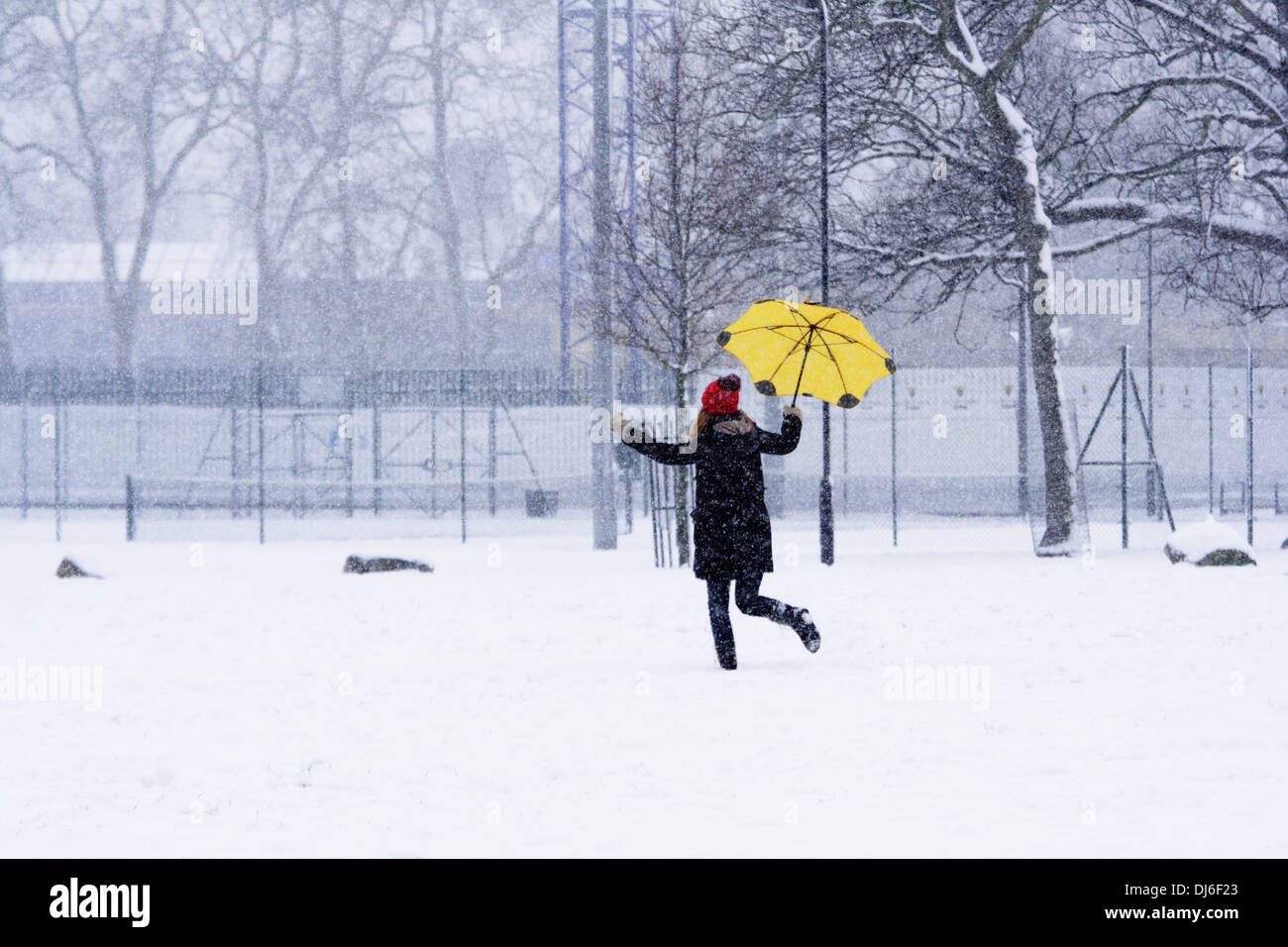 Ragazza con un ombrello giallo in una scena invernale a Hackney downs park east London Foto Stock
