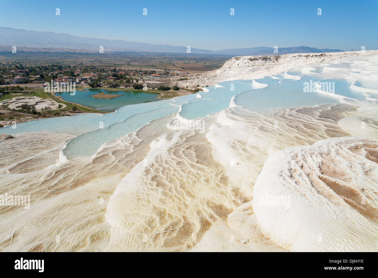 La vista dalla cima di Pamukkale. La città e le montagne al di là. Piscine formata facendo precipitare il calcio Foto Stock