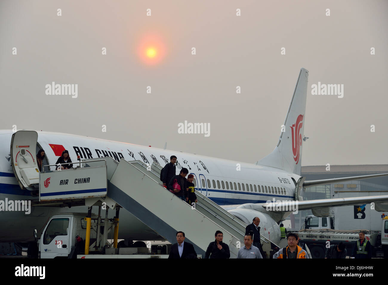 I passeggeri in partenza di un aereo in pesantemente aria inquinata all'aeroporto di Pechino. Pechino, Cina. Foto Stock