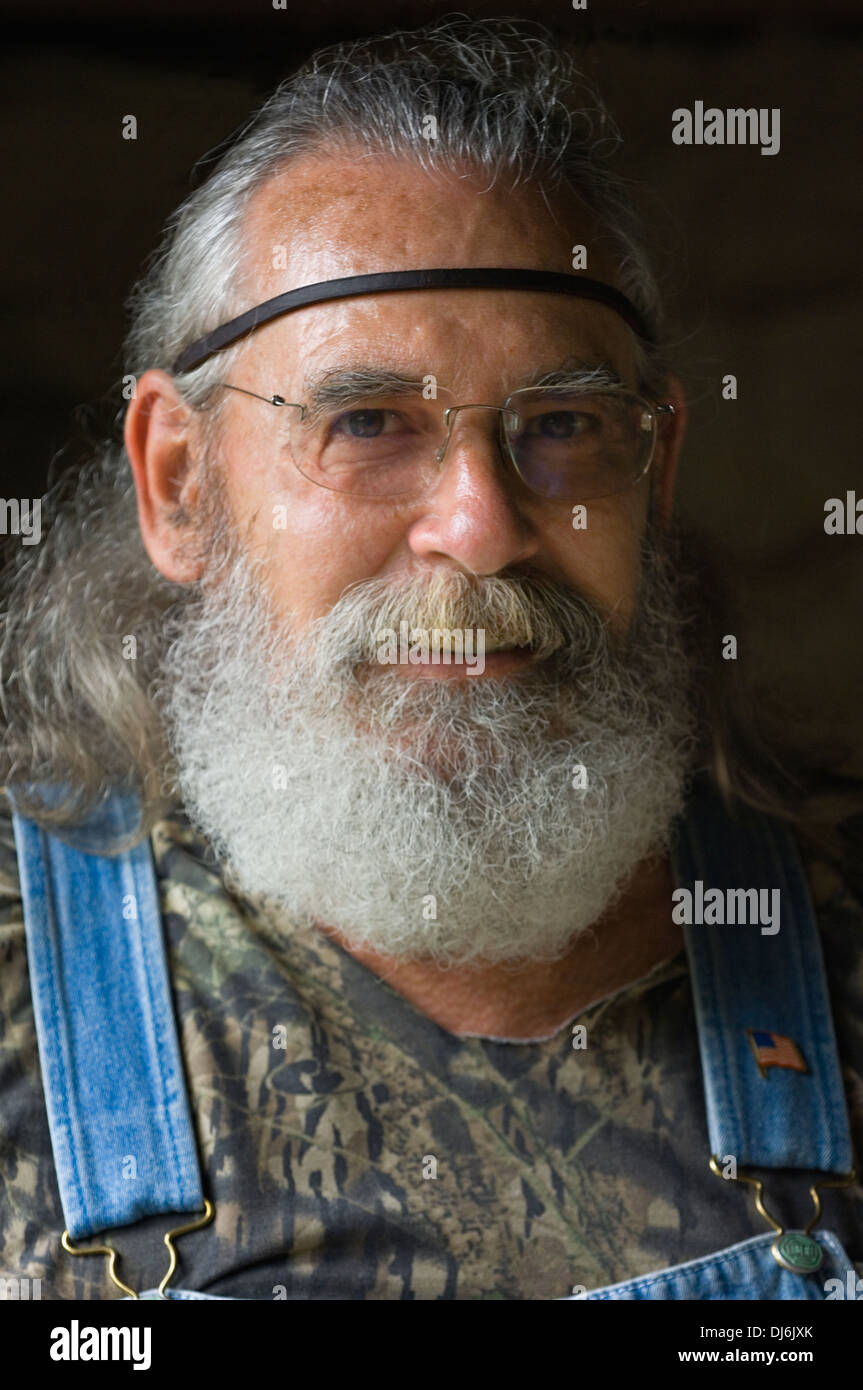 Ritratto di uomo con piena barba grigia, i capelli lunghi e la Bib-e-bretella tuta in jeans Foto Stock