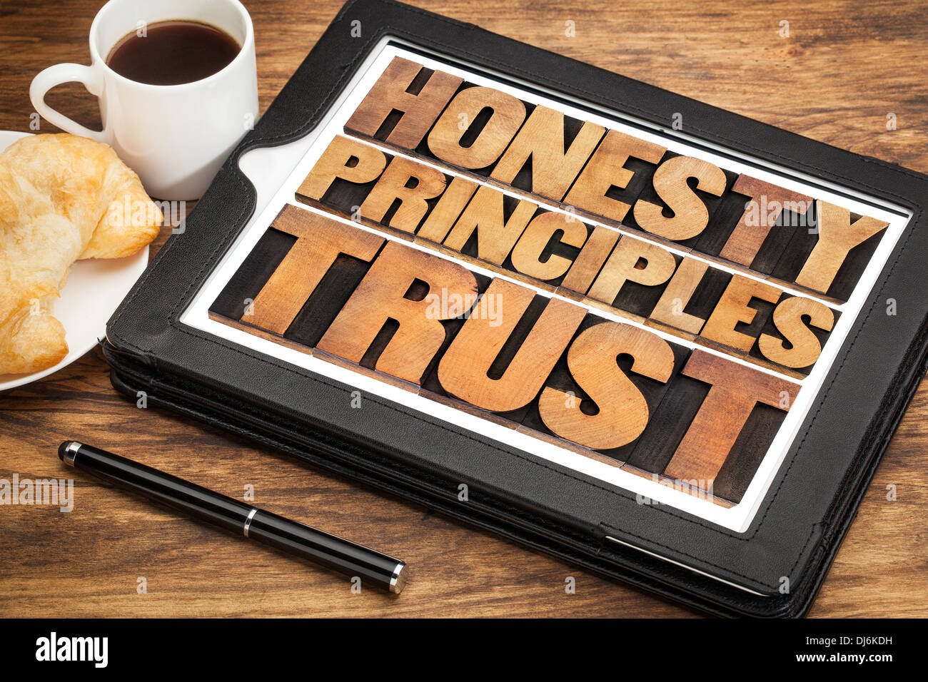 Onestà, principi e fiducia le parole in rilievografia vintage tipo di legno su un touchscreen della tavoletta digitale con una tazza di caffè Foto Stock