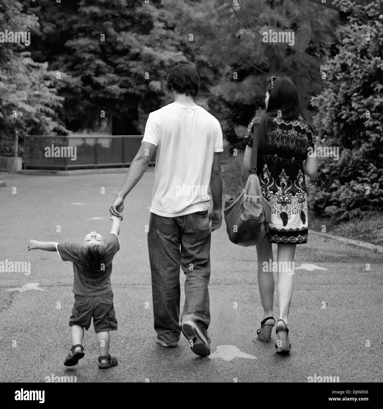 Famiglia giovane con due anni di vecchio ragazzo camminando sotto la pioggia allo Zoo Foto Stock