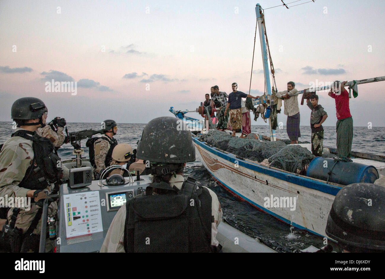 US Navy i marinai con la visita, scheda, ricerca e sequestro team dall'USS Mason tirare a fianco di una dhow di pesca in uno scafo rigido barca gonfiabile per verificare se è necessaria assistenza Novembre 20, 2013 nel Golfo di Aden. La Marina controlla regolarmente le piccole imbarcazioni nella regione per i pirati. Foto Stock