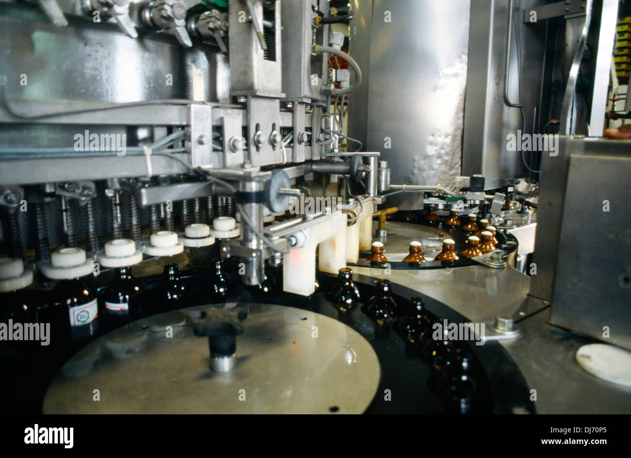 Kingston in Giamaica la striscia rossa di bottiglie di birra essendo riempito sul nastro trasportatore in fabbrica Foto Stock