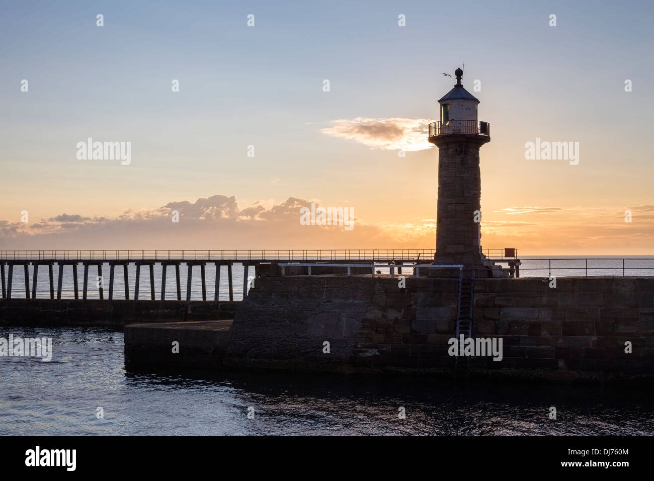 Sunrise uovere Whitby ad est del molo e il faro, North Yorkshire. Foto Stock