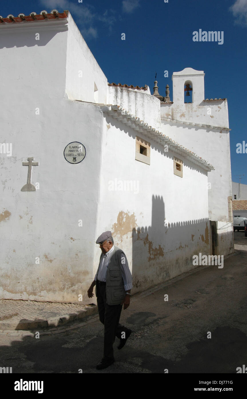 Un uomo anziano cammina oltre la chiesa di Igreja Matriz de Loule ou Igreja de Sao Clemente nella città di Loule, in Algarve, la regione più meridionale del Portogallo Foto Stock