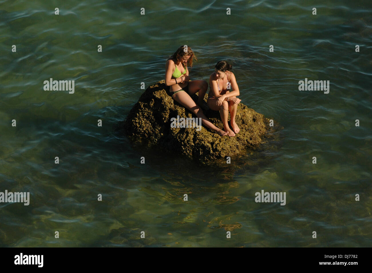 Giovani bagnanti posa su una roccia in Praia da Batata noto localmente come la spiaggia cittadina nella città di Lagos in Algarve la regione più meridionale del Portogallo Foto Stock