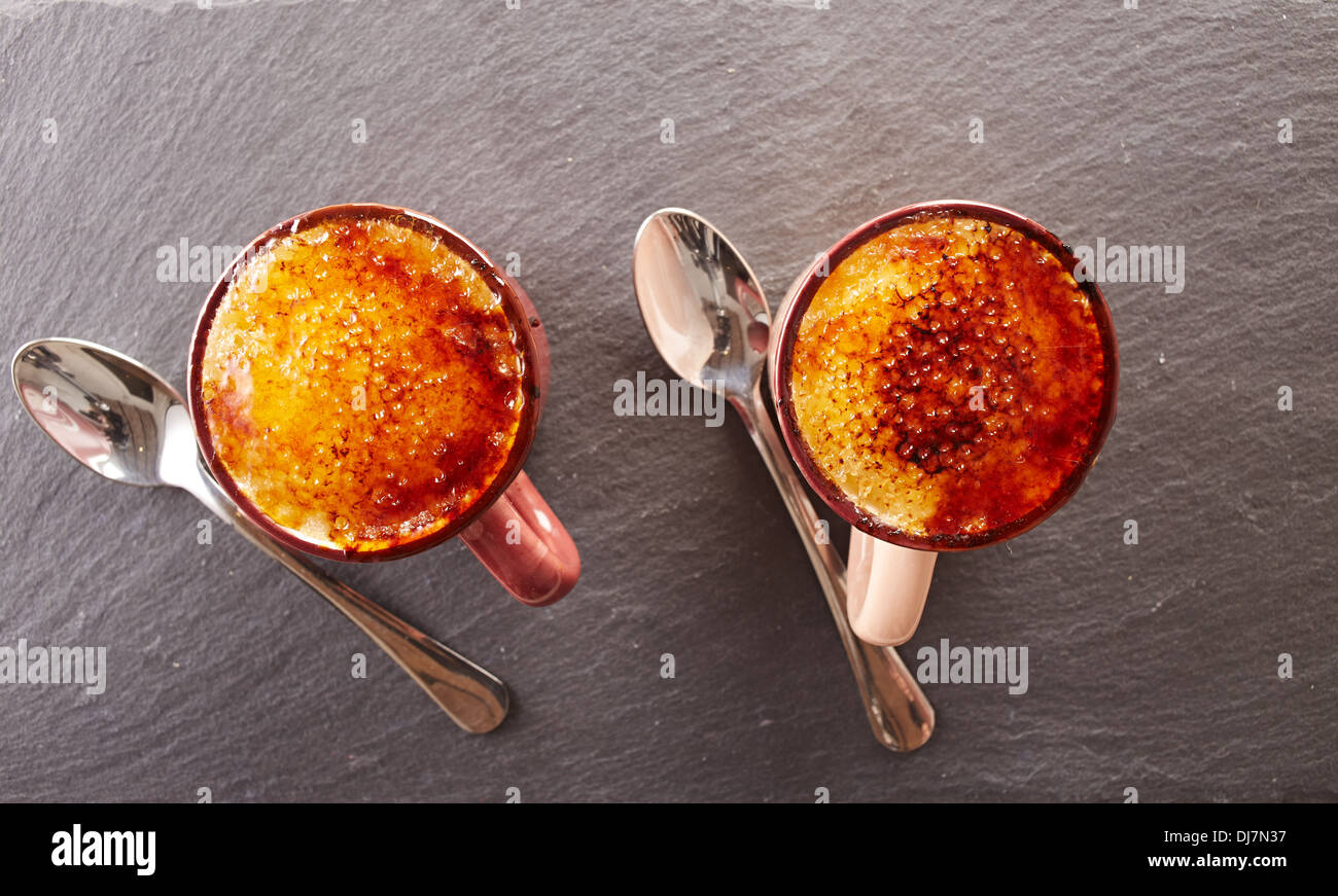 Due tazze di creme brulee su una scheda di ardesia si affacciano shot Foto Stock