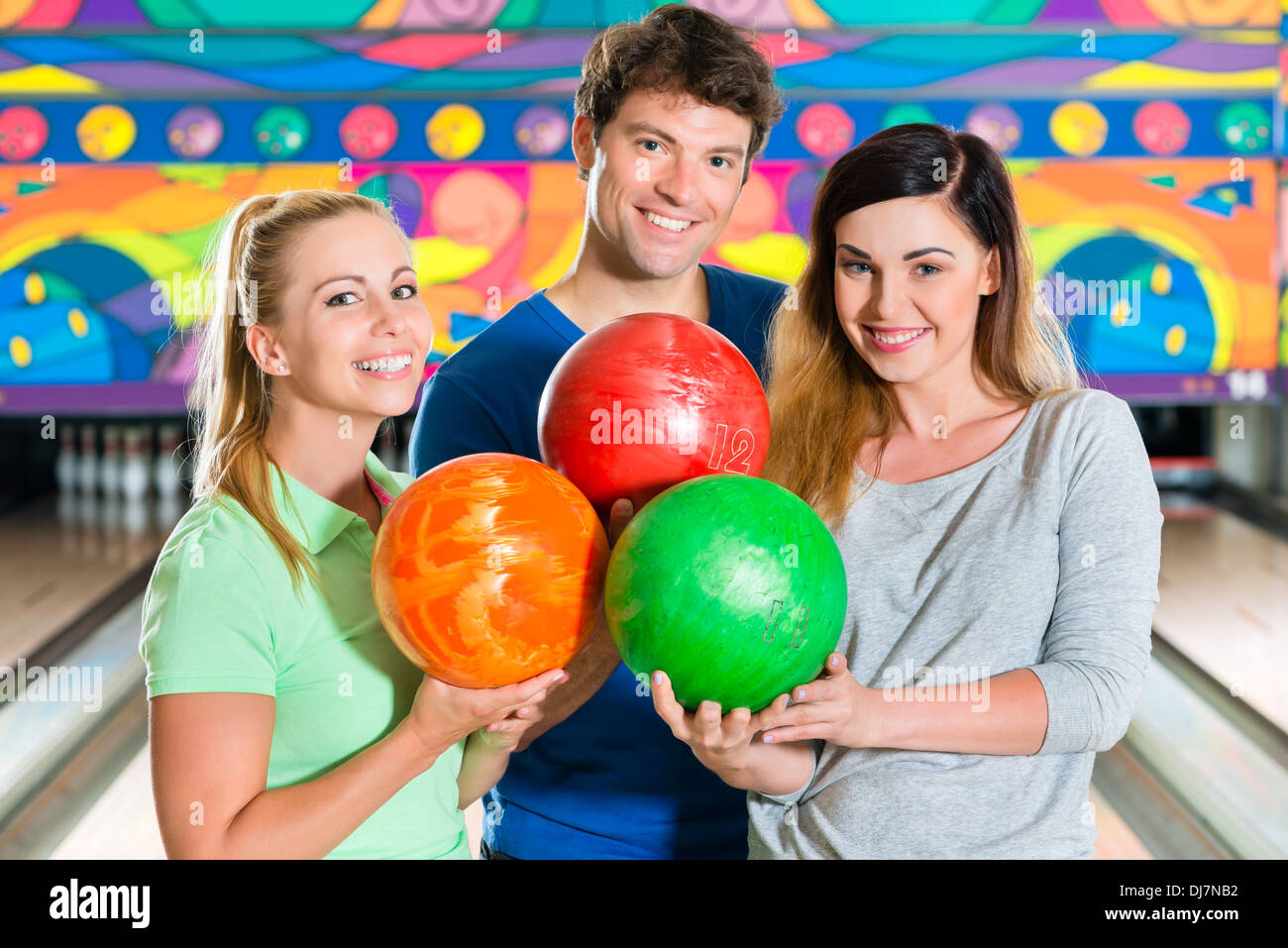 I giovani o gli amici, uomo e donna, giocare a bowling con una palla nella parte anteriore del ten pin alley, essi sono un team Foto Stock