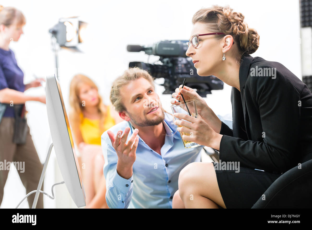 Team o Direttore discutendo durante una pausa della direzione di scena sul set di un video commerciali di produzione o di reportage in corrispondenza di una schermata Foto Stock