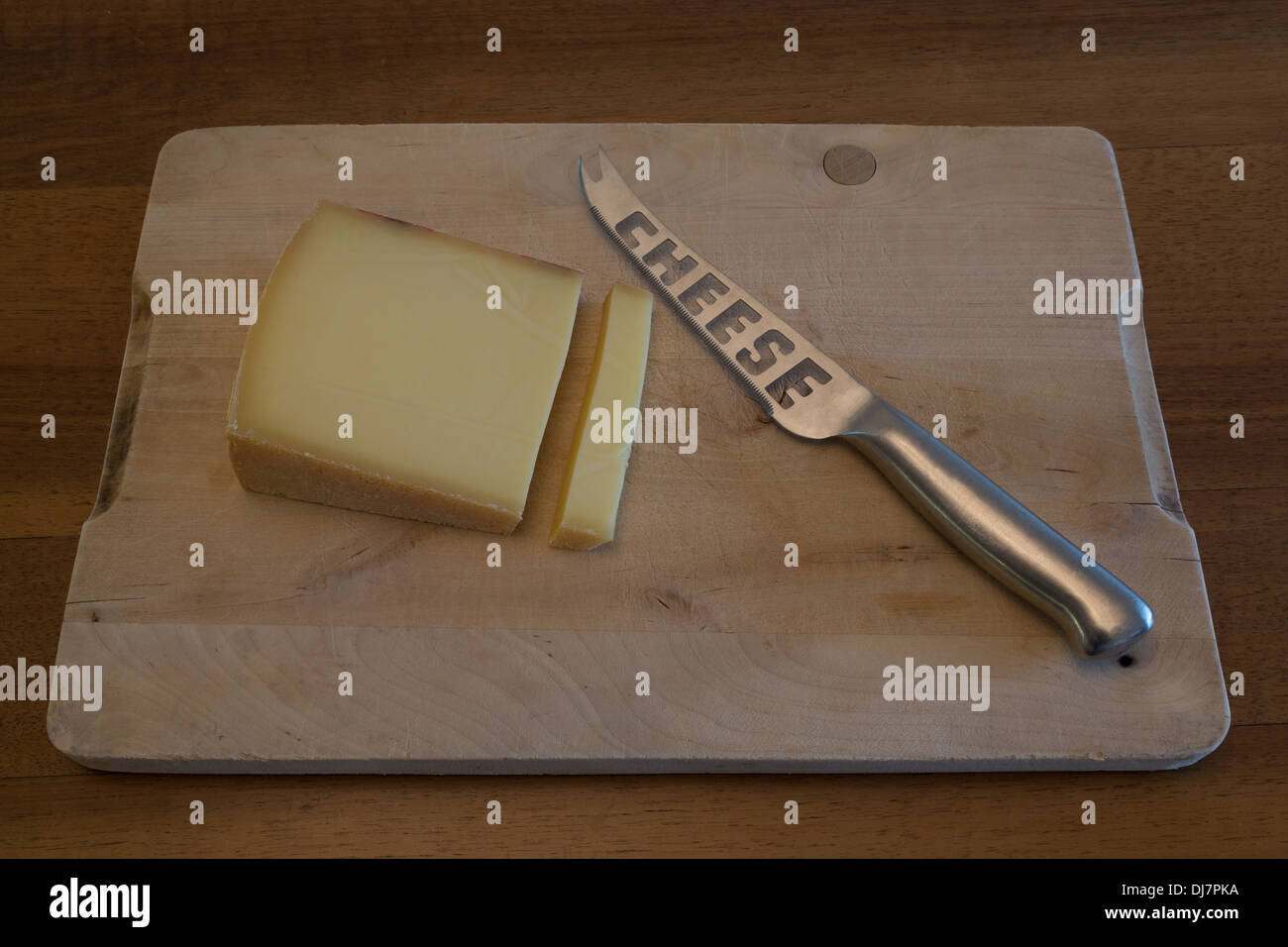 Una fotografia di alcuni formaggi svizzeri con un coltello per formaggio su un tagliere di legno. Si tratta di formaggio gruviera. Foto Stock