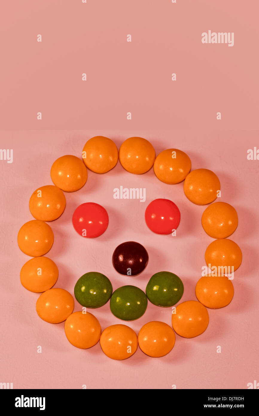 Multi-caramelle colorate disposte in forma di divertente faccia su sfondo bianco Foto Stock