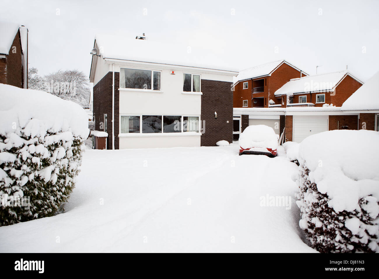 Una casa in Lincoln con un auto sul viale di accesso sia coperto di neve a seguito di una forte nevicata Foto Stock