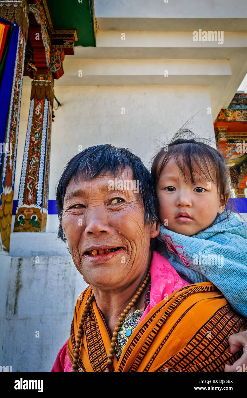 Vecchia Signora bhutanesi, la nonna bambino portando in un sacco sulla schiena Foto Stock