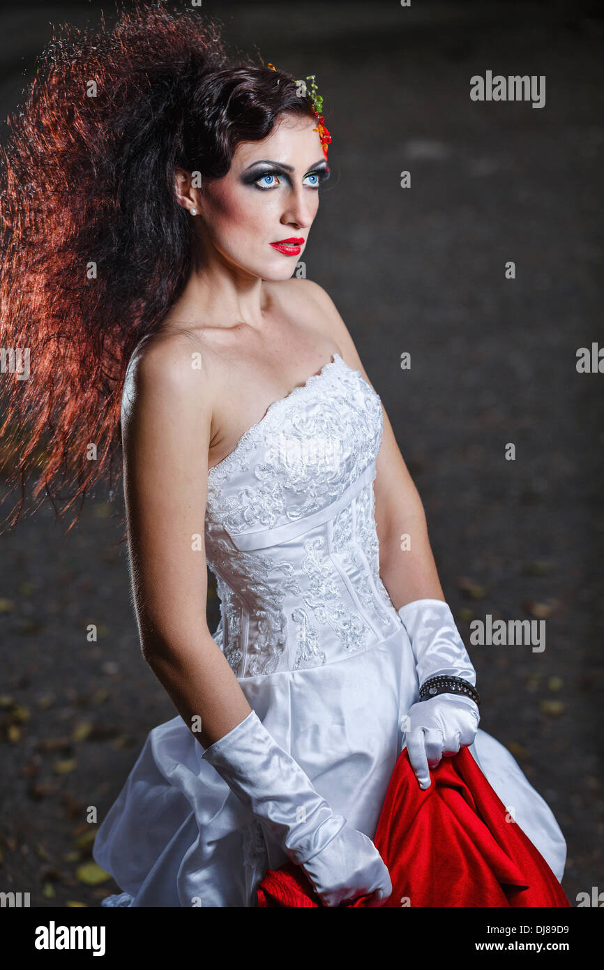 Sposa attraente in un abito da sposa con brillante trucco, scialle rosso Foto Stock