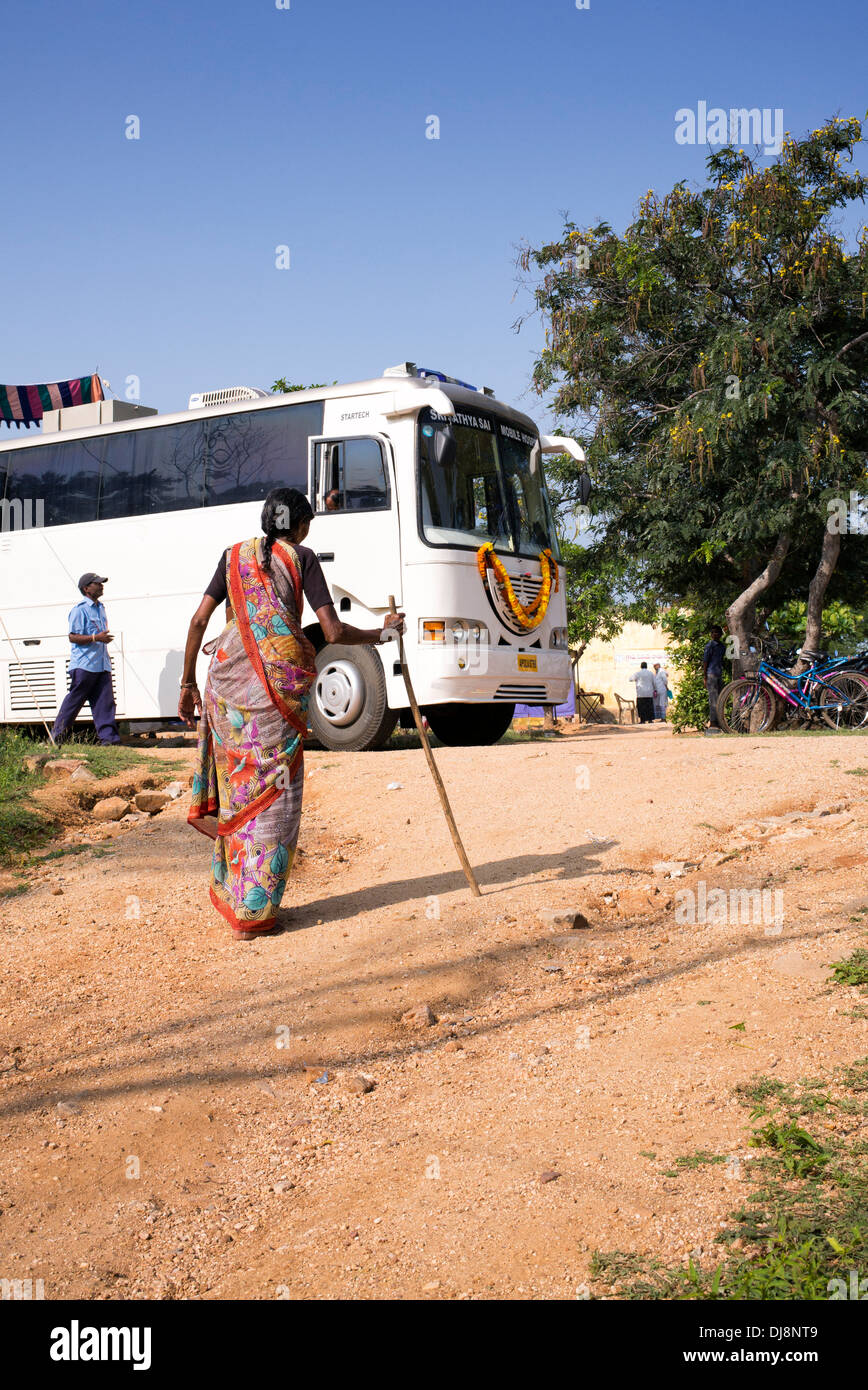 Anziani donna indiana a piedi Sri Sathya Sai Baba mobile outreach bus hospital Clinic. Andhra Pradesh, India Foto Stock