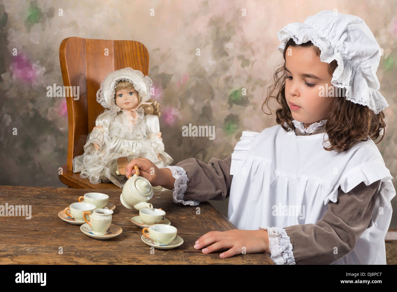 Dolce ragazza vittoriana che pongono in vecchio stile con un antico teiera Foto Stock