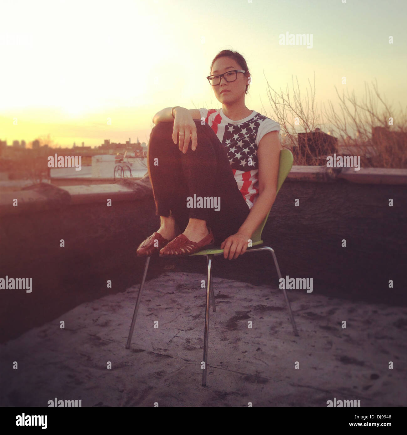 Donna seduta sul tetto urbano - Immagine stock catturata con smartphone