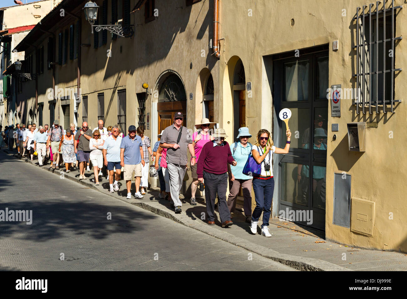 Gruppo turistico con guida femmina tenendo una paletta con il numero 8, Firenze, Italia Foto Stock