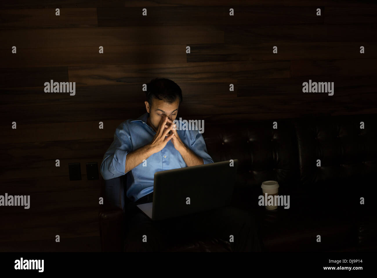 Uomo d affari con computer portatile sul divano di notte Foto Stock