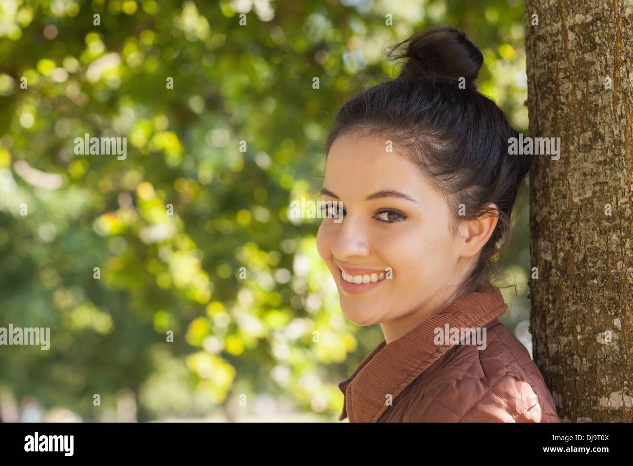 Bella giovane donna in posa appoggiato a un albero Foto Stock