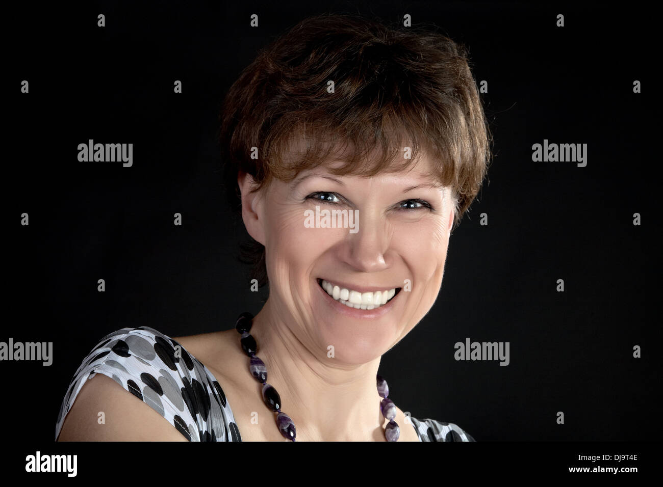 La donna sorridente di anni medi su sfondo nero Foto Stock