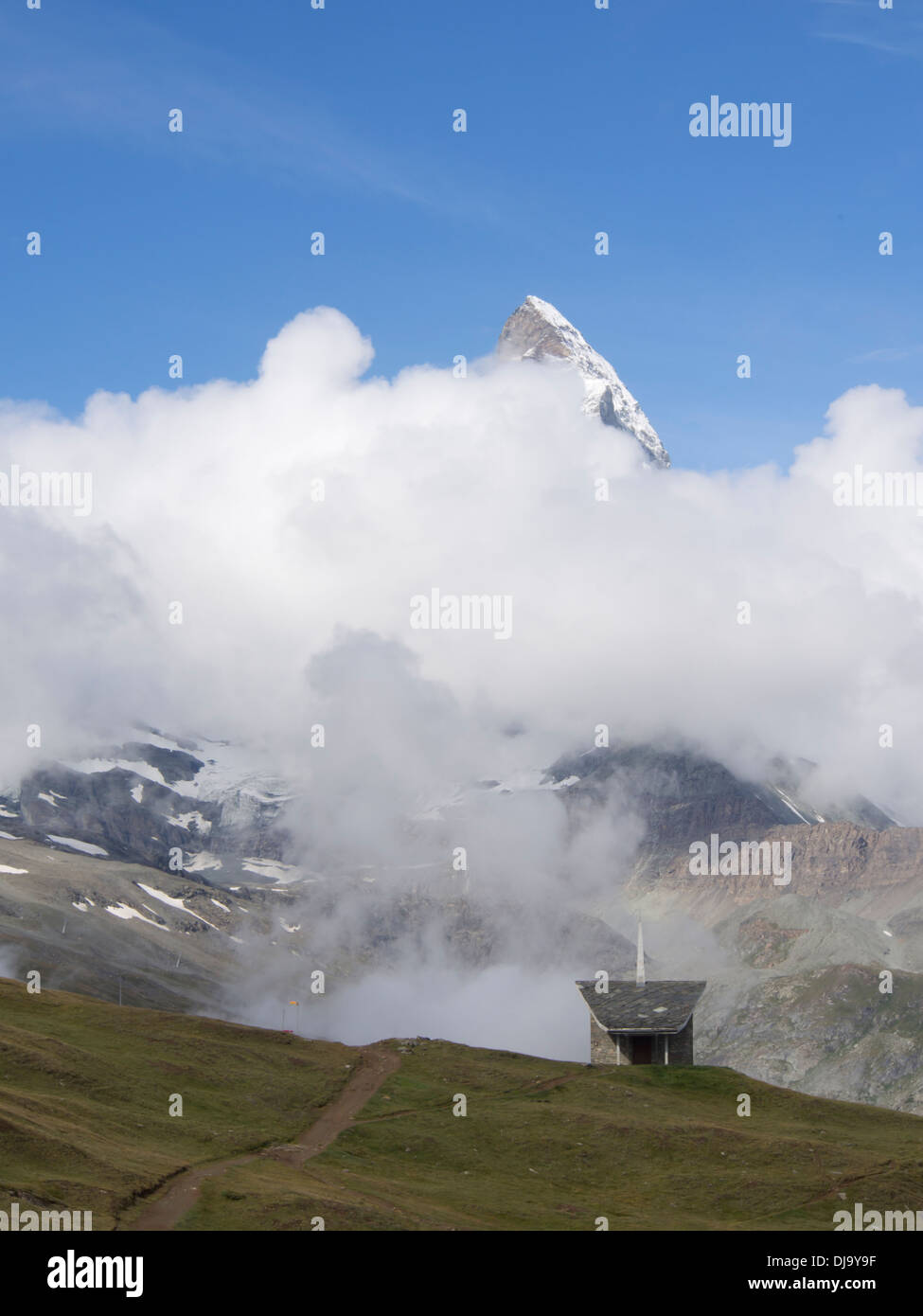 Matterhorn peak emergenti dalle nuvole,la cappella e il sentiero al vicino albergo riffelberg zermatt in Svizzera le alte alpi svizzere Foto Stock