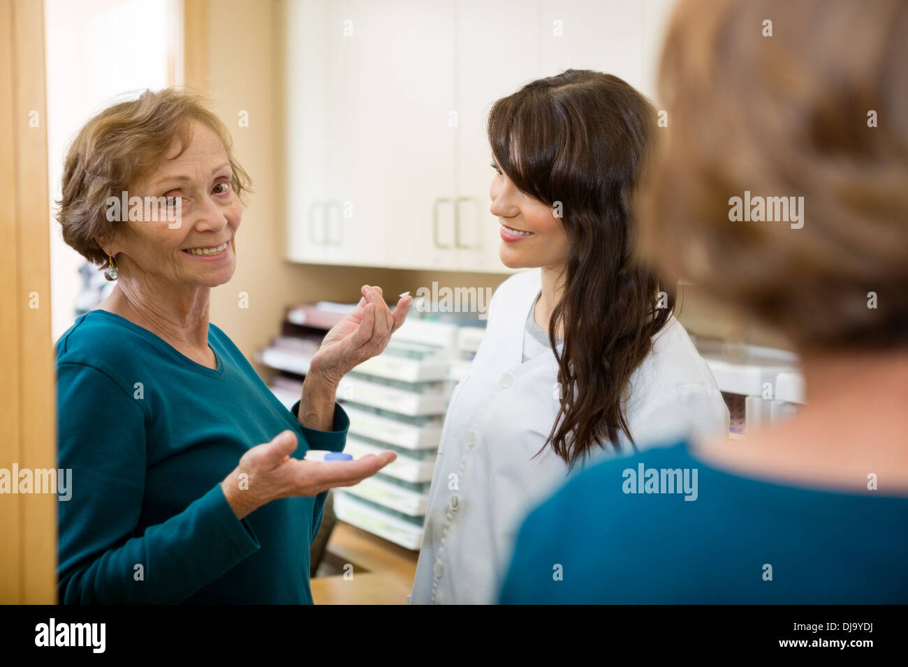 All'ottico optometrista guardando alla donna che mantiene la lente a contatto Foto Stock