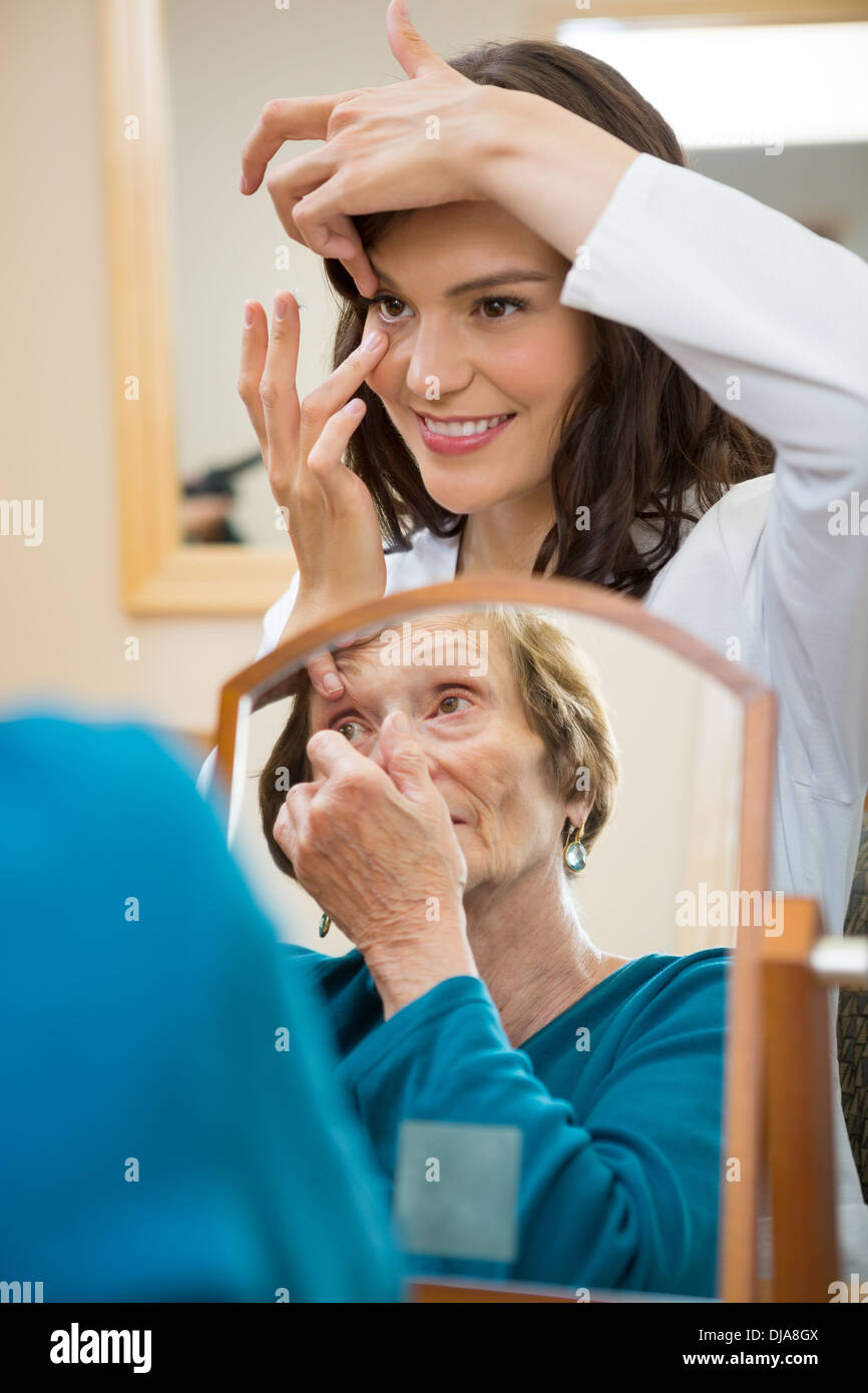 Eyecare insegnamento medico donna Senior per inserire la lente a contatto Foto Stock