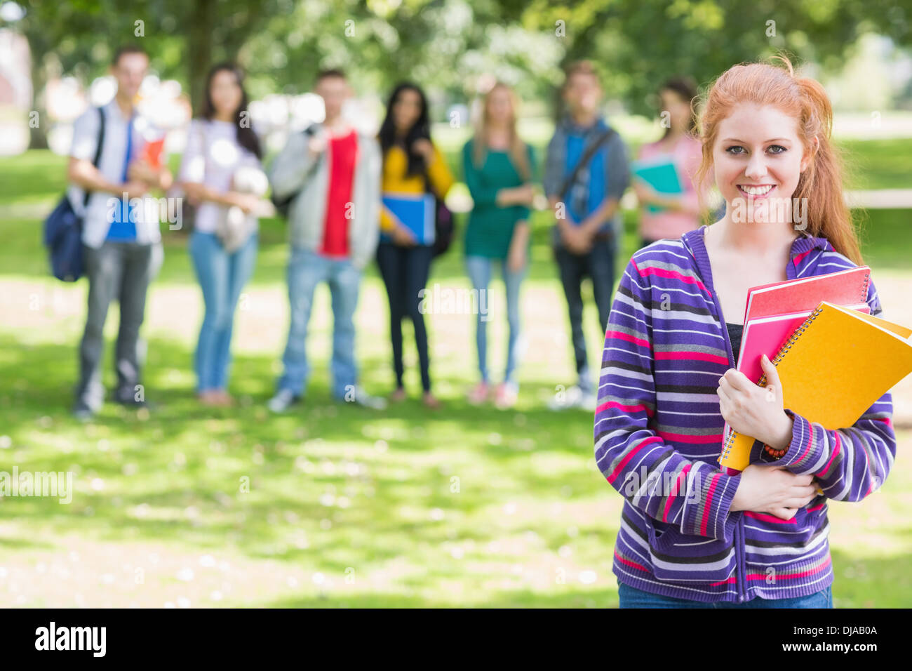 College ragazza con i libri con gli studenti in posizione di parcheggio Foto Stock