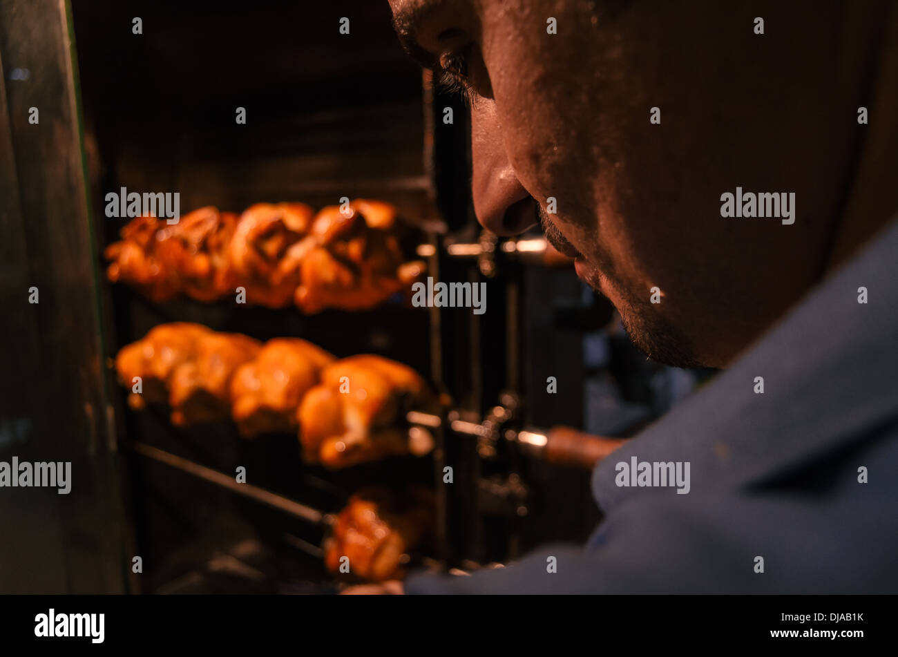 Una persona che partecipa ad un negozio di vendita allo spiedo pollo arrosto nelle strade di Deira. Dubai, Emirati Arabi Uniti. Foto Stock