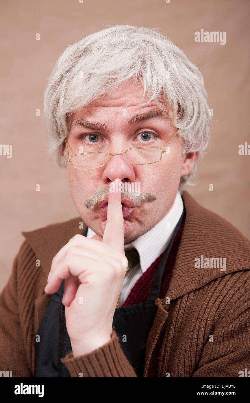 Capelli grigi vecchio uomo che chiede allo spettatore di essere tranquillo e rendendo la mano gesto del dito per labbra. Foto Stock