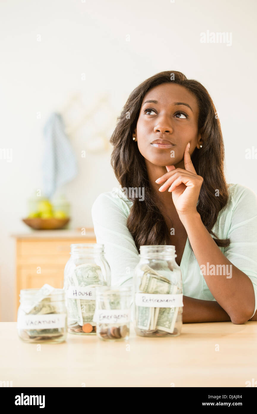 Nero donna mettere soldi in vasi di risparmio Foto Stock