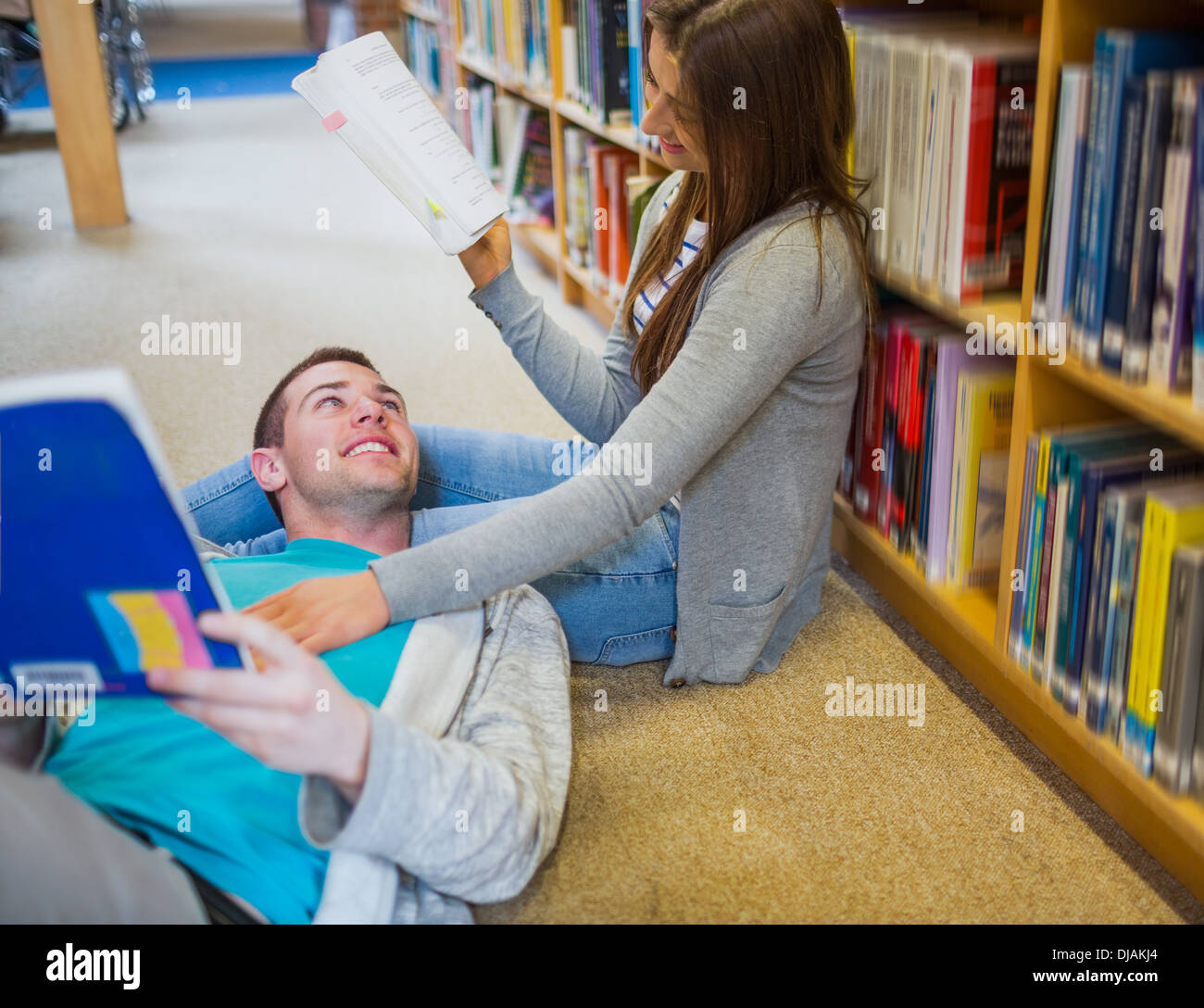 Coppia con libri in biblioteca corsia Foto Stock