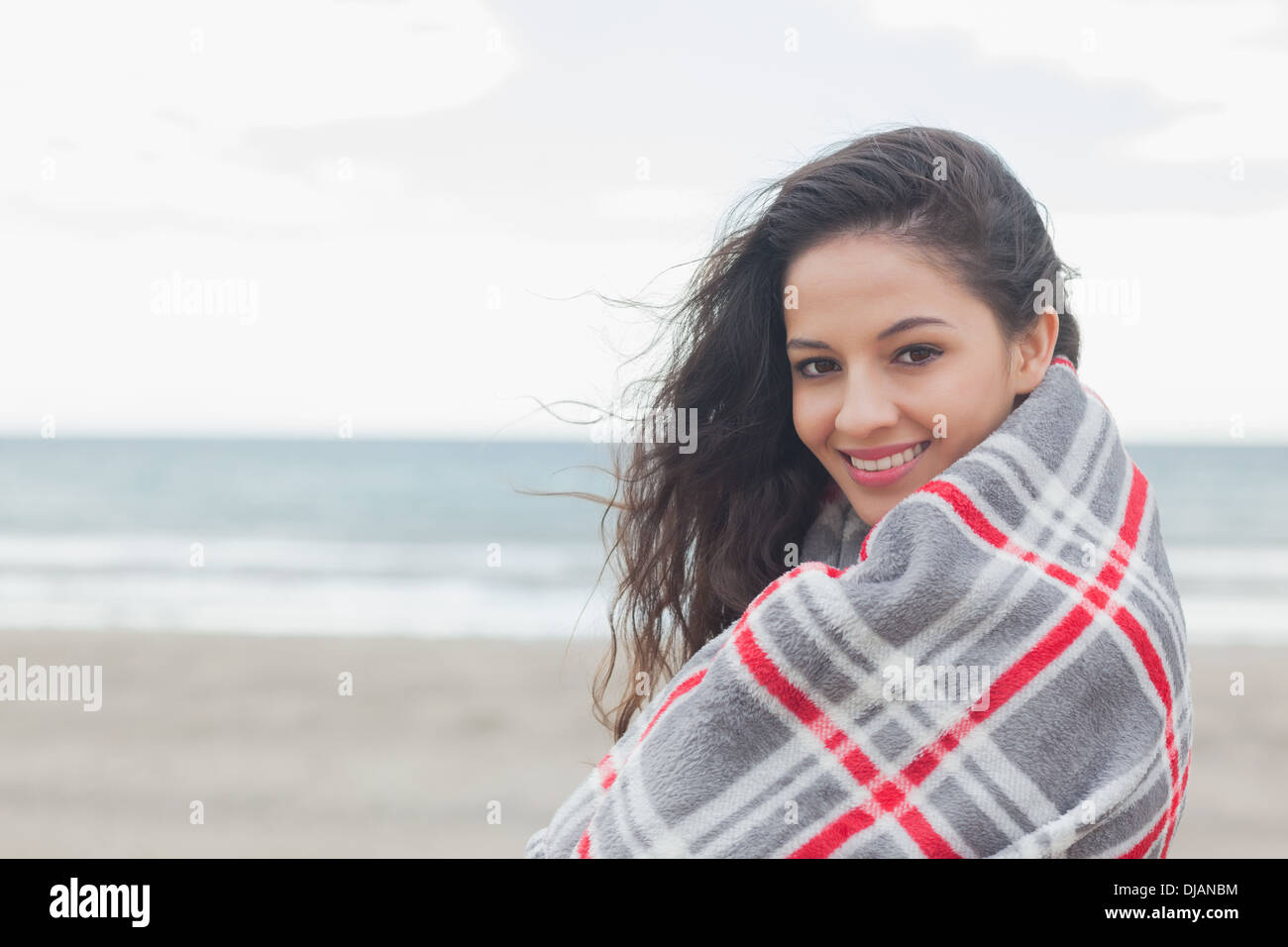 Ritratto di donna coperta con coperta in spiaggia Foto Stock