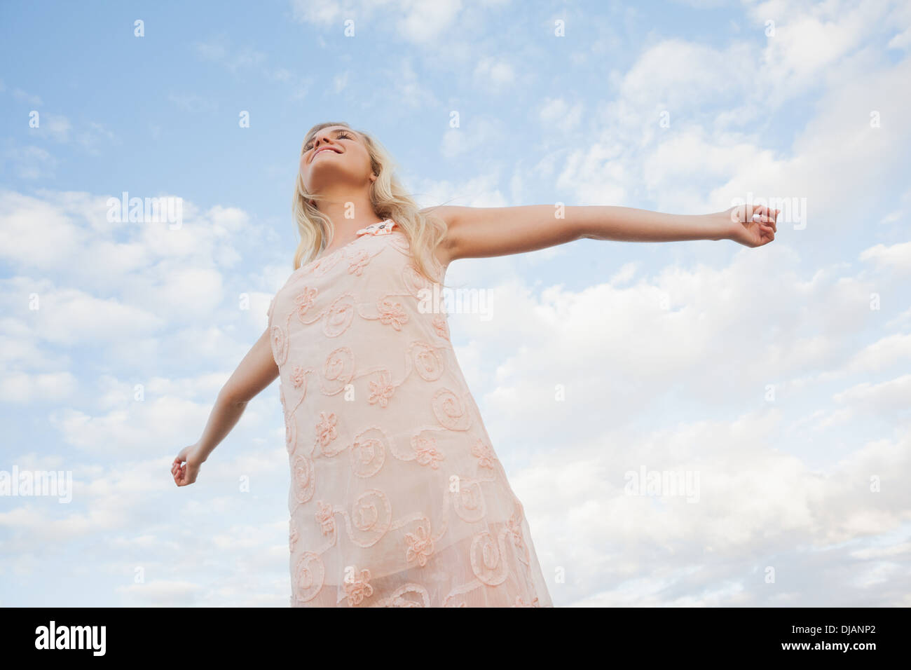 Giovane donna in abiti estivi bracci di estensione contro sky Foto Stock