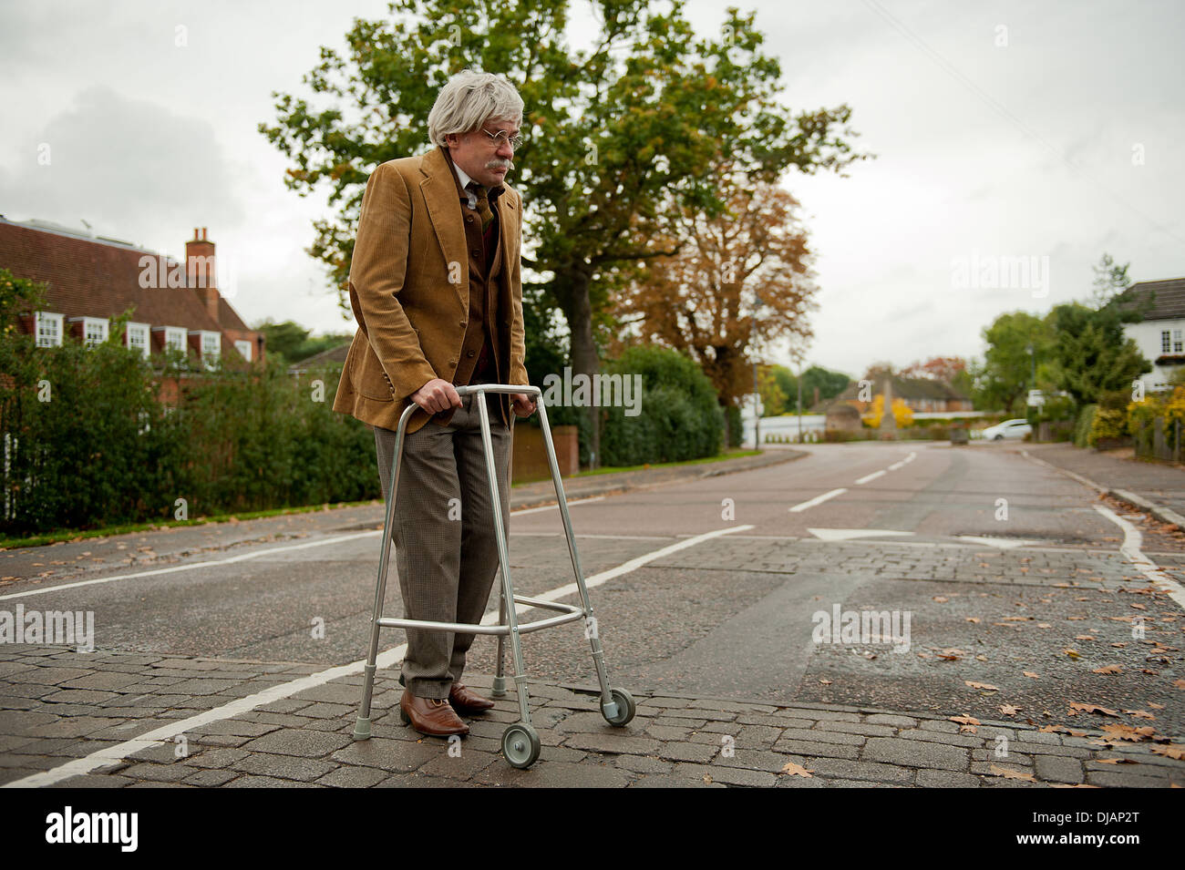 Capelli grigi uomo vecchio attraversando la strada e con l'aiuto del suo telaio camminano. Foto Stock