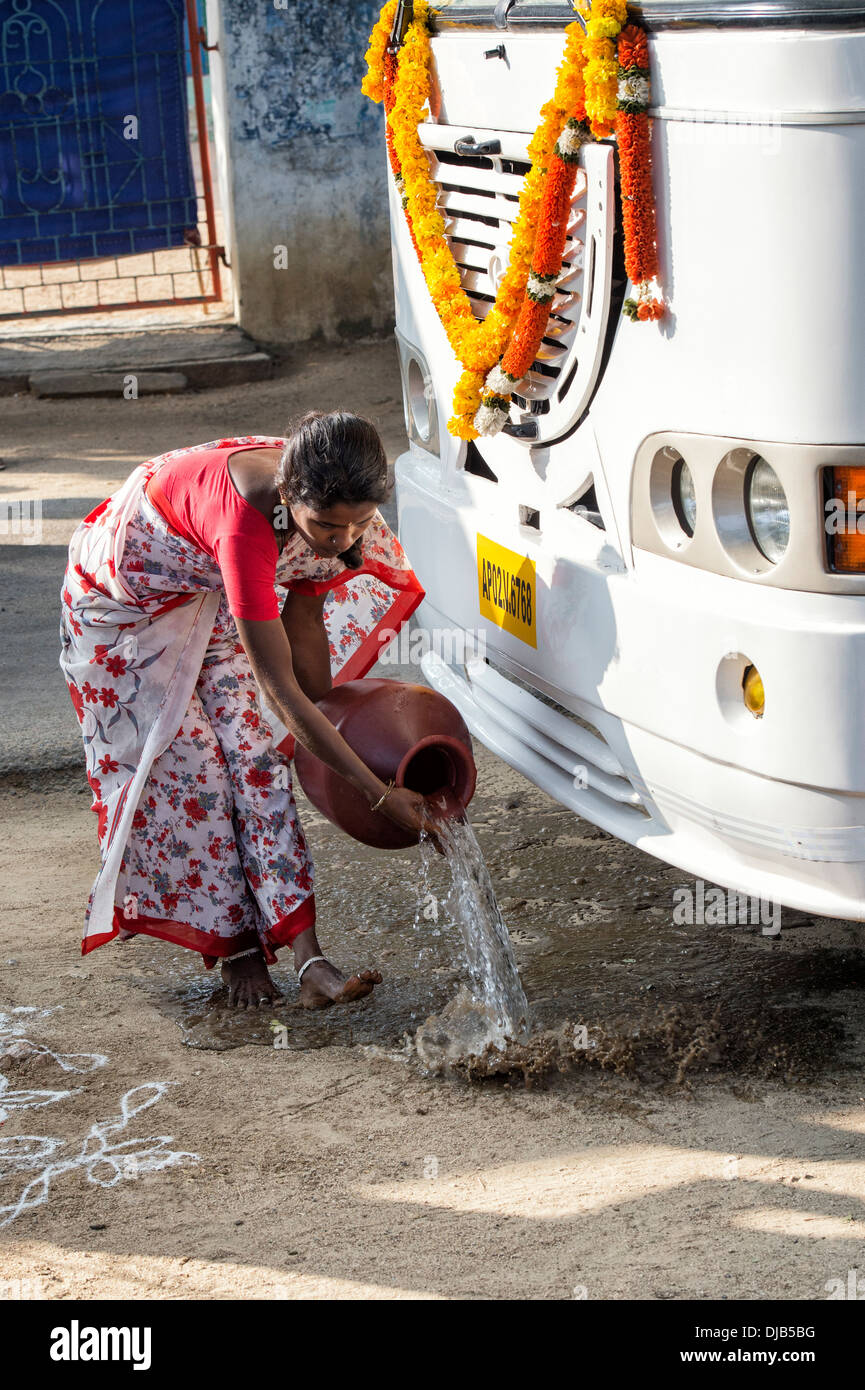 Donna indiana versando acqua prima puja nella parte anteriore del Sri Sathya Sai Baba mobile outreach bus dell'ospedale. Andhra Pradesh, India Foto Stock