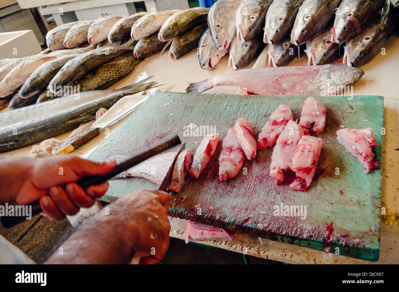 Esperto macellaio trinciatura di pesce con un coltello affilato sulla parte superiore di una sanguinosa pensione a Deira il mercato del pesce. Dubai, EAU. Foto Stock