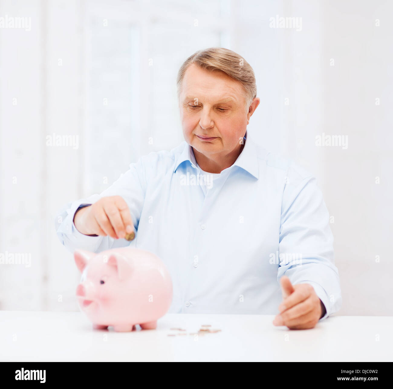 Il vecchio uomo di mettere moneta nella grande salvadanaio Foto Stock