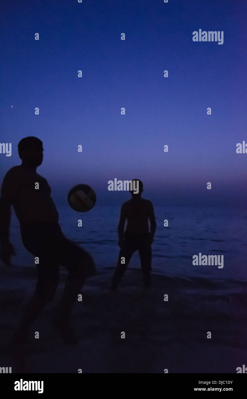 Due giovani uomini a giocare con un pallone da calcio durante il tramonto a aprire Jumeirah Beach. Dubai, EAU. Foto Stock