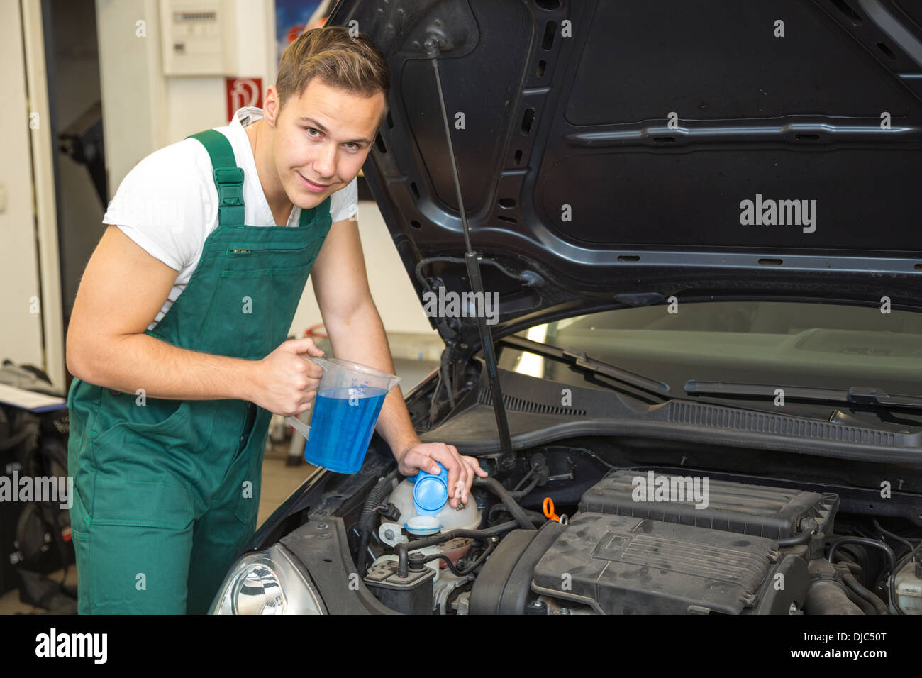 Mechanic ricariche di liquido di raffreddamento o liquido di raffreddamento nel motore di una automobile Foto Stock
