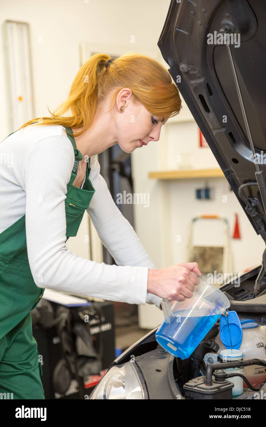 Meccanico femmina ricariche di liquido di raffreddamento o liquido di raffreddamento nel motore di una automobile Foto Stock